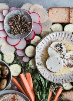 米兹（Mezze）拼盘，上面有白豆鹰嘴豆泥，混合橄榄，苹果酱，生蔬菜和蓝色桌子上的各种饼干。