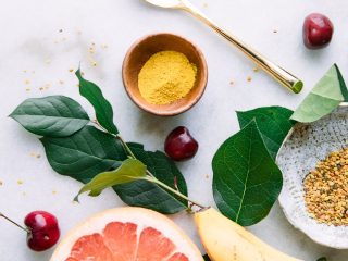 大理石桌上的黄色超级食品包括香蕉，葡萄柚，姜黄和蜜蜂花粉。