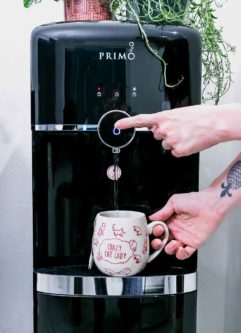 两只手将水从Primo水分配器中分配到咖啡杯中