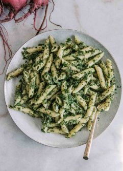 Penne Pasta面条，用甜菜制成的香蒜酱在白盘上用金叉和红色甜菜制成的香蒜酱在后台