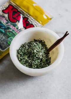 一小碗干guacas草药在一张白色桌子上，带有Guascas Herb包在后台